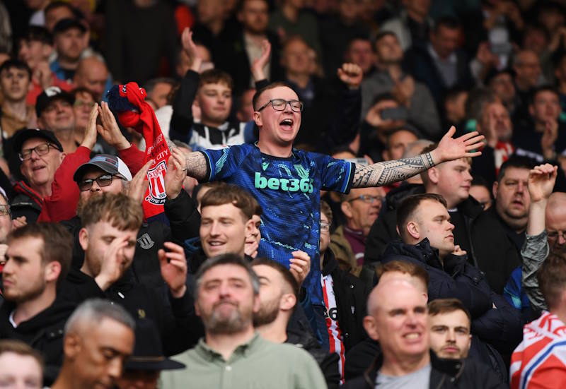 Stoke City fan stands with arms outstretched